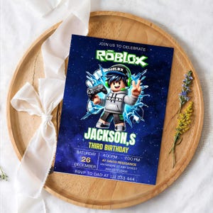 May include: A rectangular birthday invitation card featuring a dark blue space background with a Roblox character holding a game controller. The text reads JOIN US TO CELEBRATE ROBLOX, JACKSON,S THIRD BIRTHDAY, SATURDAY 26 DECEMBER, 4:00PM - 7:00PM.