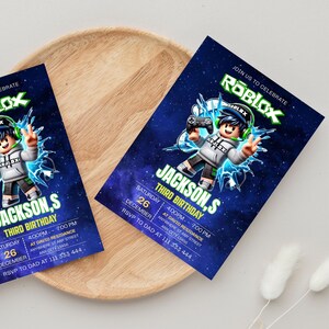 May include: Two rectangular party invitations featuring a Roblox theme with a dark blue space background. The design includes a cartoon character holding a game controller, the text "ROBLOX," "JACKSON,S THIRD BIRTHDAY," and event details.