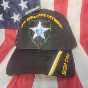 Könnte beinhalten: Schwarze Baseballkappe mit dem Emblem der 2. Infanteriedivision, einem weißen Stern mit blauen und roten Details. Auf der Kappe sind die Texte "2ND INFANTRY DIVISION" und "SECOND TO NONE" gelb gestickt.
