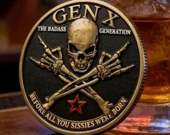May include: A circular metal coin featuring a central gold-toned skull with crossed skeletal hands making hand signs. The black background includes the text GEN X THE BADASS GENERATION and BEFORE ALL YOU SISSIES WERE BORN with a small red star.