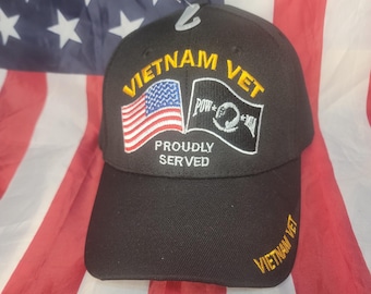 May include: Black baseball cap with the text "VIETNAM VET" in gold lettering. The cap features an American flag patch and a POW/MIA emblem. The words "PROUDLY SERVED" are also displayed.