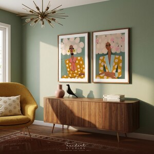 Funny wall art in mid-century modern living room — two women illustration prints above walnut credenza, mustard boucle armchair and sputnik chandelier ceiling