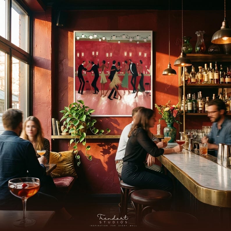 May include: Interior shot of a bar with a painting of dancers on the wall. The bar has a marble counter and shelves of bottles. People are seated at the bar and tables, drinking cocktails. The walls are painted a deep red.