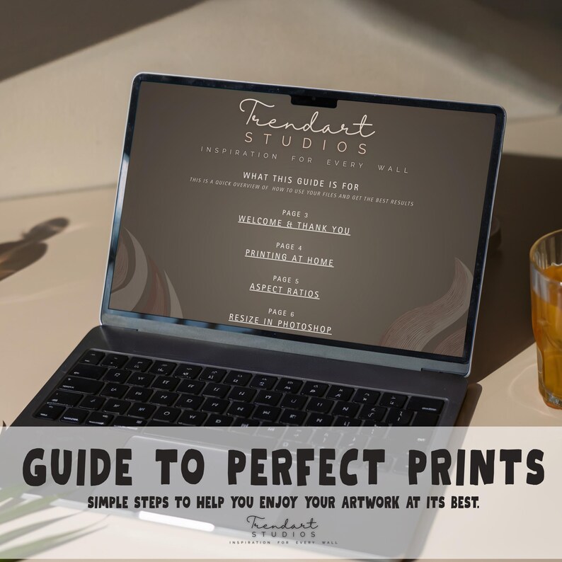 A laptop computer displaying a digital PDF guide titled Guide to Perfect Prints by Trendart Studios. This instructional material helps customers with printing at home, aspect ratios, and resizing their high-quality printable art files for best results.
