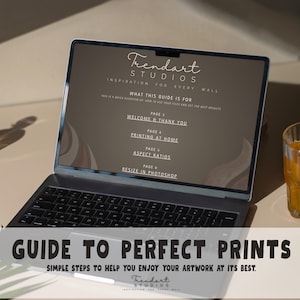 Laptop screen displaying a digital guide to perfect prints manual next to a glass of juice on a desk