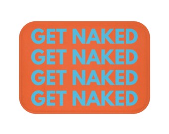 Op de afbeelding: Een oranje rechthoekige badmat met afgeronde hoeken. De woorden "GET NAKED" zijn lichtblauw gedrukt, vier keer herhaald. De tekst is gecentreerd op de mat.