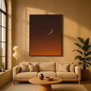 May include: A modern living room with a beige sofa, round wooden coffee table, and a large framed art piece depicting a crescent moon against a gradient orange and brown sky. A potted plant and a floor lamp add to the decor.