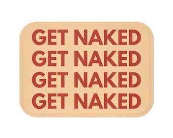 Op de afbeelding: Een rechthoekige badmat met afgeronde hoeken. De mat is lichtbeige van kleur en de woorden "GET NAKED" zijn in een herhalend patroon gedrukt in een vet, roodbruin lettertype.