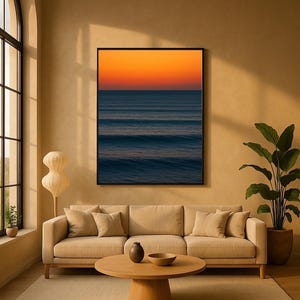 May include: A living room with a beige sofa, round wooden coffee table, and a large framed artwork depicting an ocean sunset. A floor lamp and potted plant add to the decor. The room has a neutral color palette.