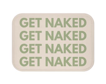 Pode incluir: Tapete de banho retangular com cantos arredondados. O tapete é bege com as palavras "GET NAKED" repetidas quatro vezes em verde sálvia. O tapete tem um design simples e minimalista.