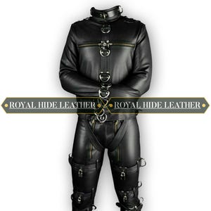 Può includere: Completo giacca e pantaloni in pelle nera con anelli e cerniere in metallo. La giacca ha un colletto alto e i pantaloni hanno cinghie e fibbie. Il testo "ROYAL HIDE LEATHER" è visualizzato su uno striscione.