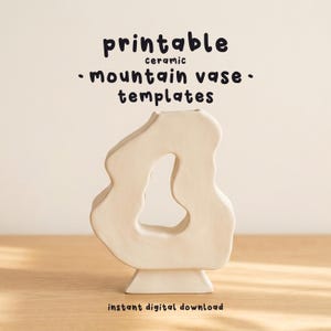 Op de afbeelding: Een crèmekleurige keramische vaas met een onregelmatige, organische vorm en een centrale uitsparing, met de tekst "printable ceramic mountain vase templates" erboven en "instant digital download" onder het object in een donker lettertype.