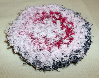 May include: A white, fluffy, round, fabric scrub with a pink and red dye pattern.