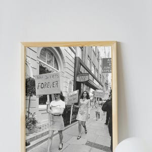 Puede incluir: Fotografía en blanco y negro enmarcada de mujeres marchando por una calle, sosteniendo carteles con las palabras "Mini faldas para siempre" y otros lemas. Escena callejera vintage.