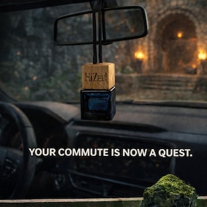 May include: Car air freshener with a wooden top and a dark blue glass base, hanging from a car's rearview mirror. The wooden top is engraved with "HiZev!". The text "WELCOME, TRAVELER. ENTER THE DUNGEON." is visible. The product is labeled "DUNGEON CRAWLER CARL CAR AIR FRESHENER" with a "MOSS SCENT".
