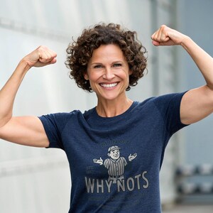 Op de afbeelding: Een marineblauw t-shirt met een cartoon scheidsrechter en de woorden "MINOT WHY NOTS" in zilver. Het shirt bevat ook de tekst "EST. 1917" en "MINOT NORTH DAKOTA".