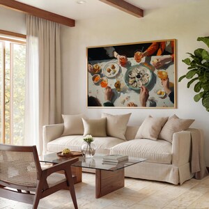 May include: A framed painting depicts a dining scene with a table set with oysters, drinks, and small plates. The painting hangs above a beige sofa with throw pillows. A glass coffee table and wooden chair are in front of the sofa.