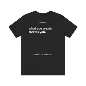 May include: A black short-sleeved t-shirt featuring white text. The top reads THEORIE. 004, followed by the phrase what you create, creates you. Below this, the text process > outcome is printed in a smaller, white sans-serif font.