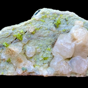 May include: A mineral specimen featuring a light green matrix with clusters of pale, translucent crystals. Small, bright green crystals are scattered across the surface. The background is solid black.