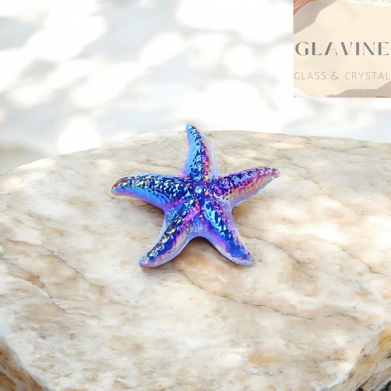 May include: A five-pointed starfish figurine with a glossy, iridescent finish that shifts between shades of blue, purple, and pink. The surface features a textured, glittery appearance that reflects light, creating a shimmering effect across the object.