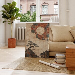 May include: A framed print of a watercolor painting depicting a stylized landscape with a large, full moon, a small pine tree, and mountains. The painting has a muted color palette of browns, blues, and grays.
