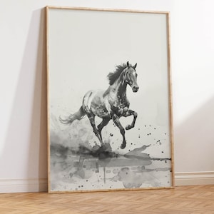 以下が含まれることがあります： フレームに入った、白黒の走る馬のアートプリント。水彩画風で、グレーと黒の飛沫が動きを表現しています。明るい木製のフレームに入った、インテリアに合うアート作品です。