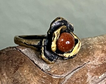 Eye catching Goldstone and Antiqued brass ring with a textured, organic flower design