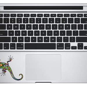 May include: A silver laptop computer with a colorful lizard sticker on the trackpad. The lizard is green, blue, red, yellow, and orange.