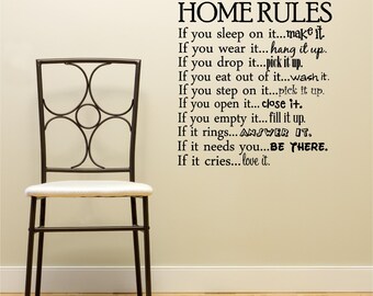 May include: A black and white wall decal with the text "HOME RULES" and a list of rules for the home. The rules are written in a playful and lighthearted tone. The decal is applied to a wall with a chair in front of it.