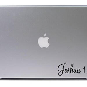 May include: A silver laptop computer with a white Apple logo and a black vinyl sticker with the text "Joshua 1:9" on the bottom right corner.