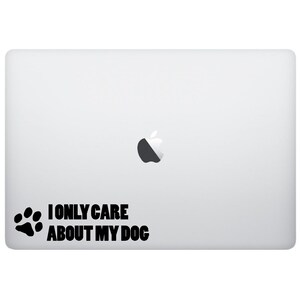 May include: A white laptop with a black Apple logo and a black paw print sticker with the text "I ONLY CARE ABOUT MY DOG".