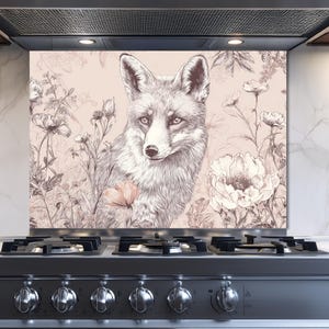 Könnte beinhalten: Eine dekorative Küchenrückwand mit einer detaillierten Illustration eines Fuchses inmitten floraler Elemente. Das Kunstwerk ist hauptsächlich in Grau- und Beigetönen gehalten und schafft eine natürliche und elegante Ästhetik. Die Rückwand ist hinter einem Edelstahlherd installiert.