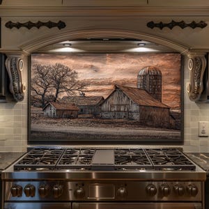 May include: A framed artwork showing a rural farm scene with a barn, silo, and bare tree under a cloudy sky. The artwork is mounted above a stainless steel gas range with multiple burners.