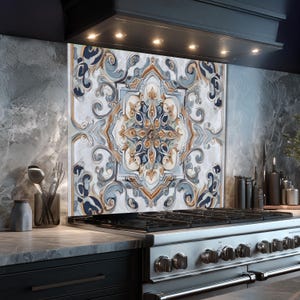 K&ouml;nnte beinhalten: Dekorative K&uuml;chenr&uuml;ckwand mit einem symmetrischen, verzierten Design. Das Muster zeigt wirbelnde blaue, goldene und wei&szlig;e Elemente. Die R&uuml;ckwand ist &uuml;ber einem Gasherd aus Edelstahl installiert und bildet einen Blickfang in der K&uuml;che.