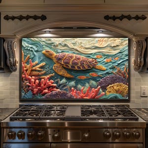 May include: A colorful, framed artwork depicting a sea turtle swimming in an ocean scene. The artwork features a detailed relief of the turtle, coral, and fish in shades of yellow, orange, red, and blue. The artwork is mounted above a stainless steel stove.