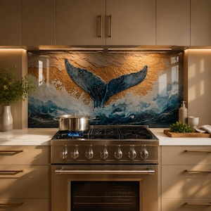 Op de afbeelding: Een keukenachterwand met een textuurrijk muurschildering van een blauwe walvisstaart die uit oceaangolven oprijst tegen een gouden achtergrond, geplaatst achter een roestvrijstalen gasfornuis met een metalen pan en beige kasten erboven.