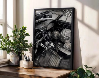 Puede incluir: Impresión enmarcada en blanco y negro del interior de un coche antiguo. La imagen presenta un volante, un salpicadero y varias bolas de discoteca dentro del coche. La impresión se exhibe sobre una superficie de madera con una planta y lápices.