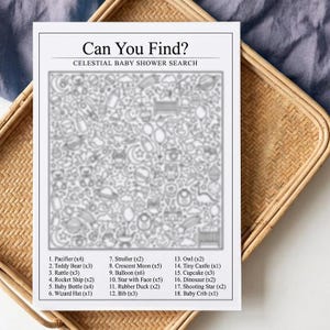 May include: A black and white baby shower search game titled "Can You Find?" with a celestial theme. The game includes a list of items to find within the image, such as pacifiers, teddy bears, and stars. The game is placed on a woven tray.