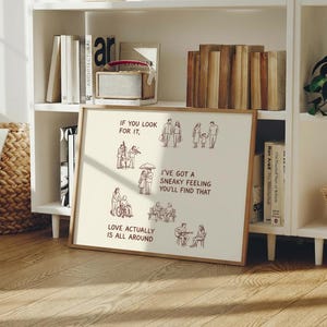 May include: A framed print with a wooden frame, featuring illustrations and text. The text reads "If you look for it, I've got a sneaky feeling you'll find that. Love actually is all around." The illustrations depict various scenes of people.