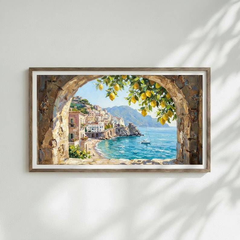 May include: A framed landscape painting depicting a coastal town with buildings nestled on cliffs overlooking a blue sea. A stone archway frames the view, with yellow lemon branches hanging in the foreground and a small white boat on the water.