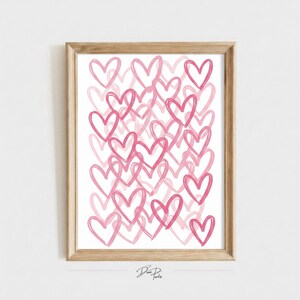 May include: A framed wall art print featuring a repeating pattern of hand-drawn pink heart outlines on a white background. The hearts vary in size and overlap, creating a dense, layered composition. The artwork is enclosed in a light wood frame.