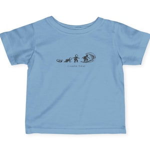 May include: Light blue toddler t-shirt with a black graphic of a surfer riding a wave. The graphic also shows a stick figure walking towards the wave. The text "Coastal Yokel" is below the graphic.