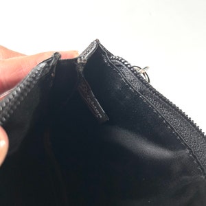 以下が含まれることがあります： シルバーのジッパープルが付いた黒いジッパーポーチ。内側は黒い生地です。「Brighton」のブランド名がポーチ内の小さなタグに表示されています。