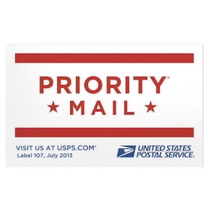 May include: White rectangular USPS Priority Mail label with red stripes and text. The words "PRIORITY MAIL" are in red, with stars. The bottom of the label includes "VISIT US AT USPS.COM" and "UNITED STATES POSTAL SERVICE."