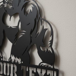 A close-up view of a black metal cutout of a gorilla, with the text "OUR TEXT" below it.