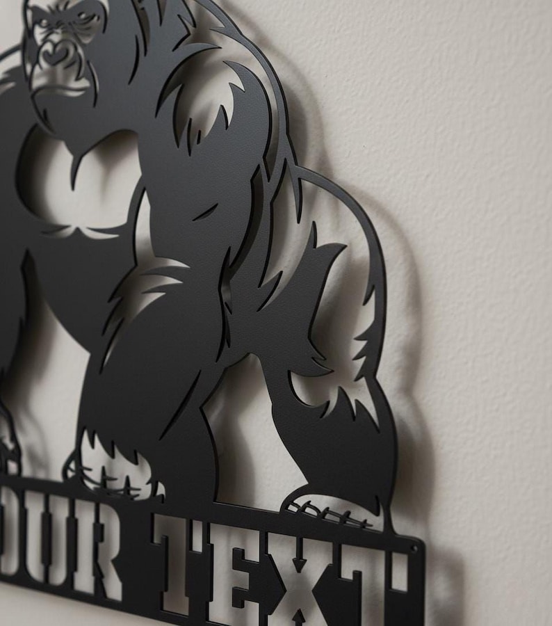 A close-up view of a black metal cutout of a gorilla, with the text "OUR TEXT" below it.