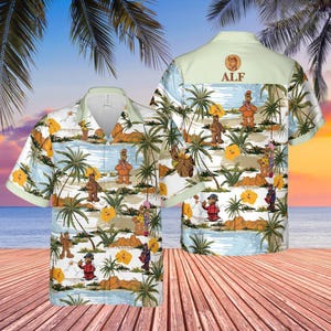 May include: A short-sleeved button-down shirt featuring a tropical scene with cartoon characters, palm trees, and yellow flowers. The shirt has a light green collar and the word "ALF" on the back.