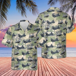 Pode incluir: Uma camisa de manga curta com um padrão repetido de helicópteros cinzentos sobre um fundo verde claro. A camisa tem uma gola clássica e um ajuste descontraído, ideal para uso casual. O design inclui palmeiras e uma cena tropical.