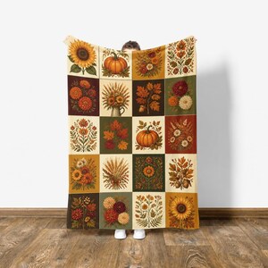 May include: A rectangular throw blanket featuring a grid pattern of twenty individual squares. Each square displays a unique autumn-themed illustration, including orange pumpkins, yellow sunflowers, various fall leaves, wheat stalks, and floral bouquets.