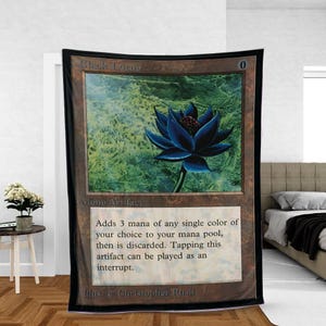May include: A large, rectangular throw blanket featuring a Magic: The Gathering card design. The card depicts a dark blue lotus flower with the text "Black Lotus" and "Mono Artifact". The blanket has a brown border.